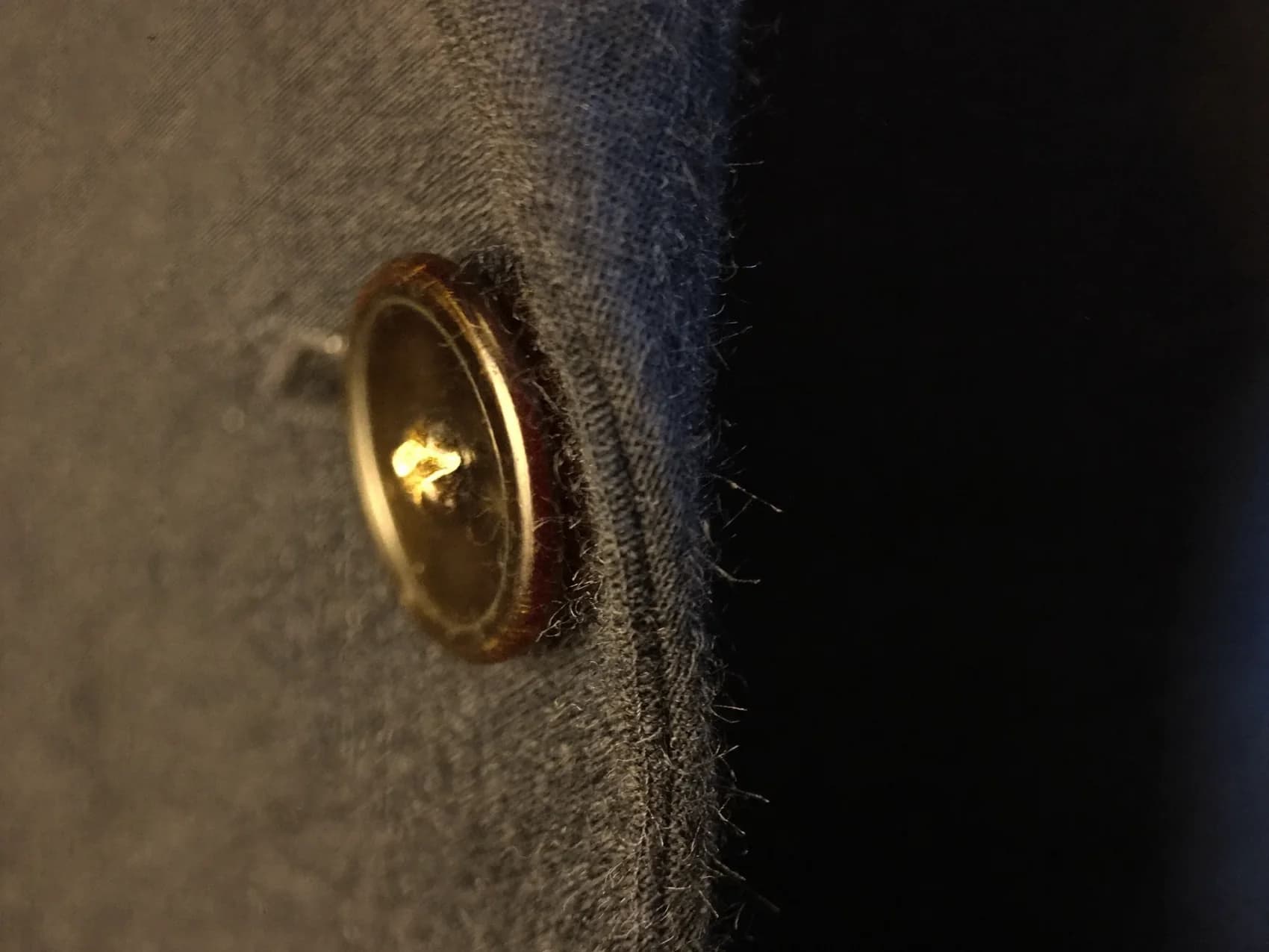 Macro detail of a hand-finished silk buttonhole in charcoal wool
