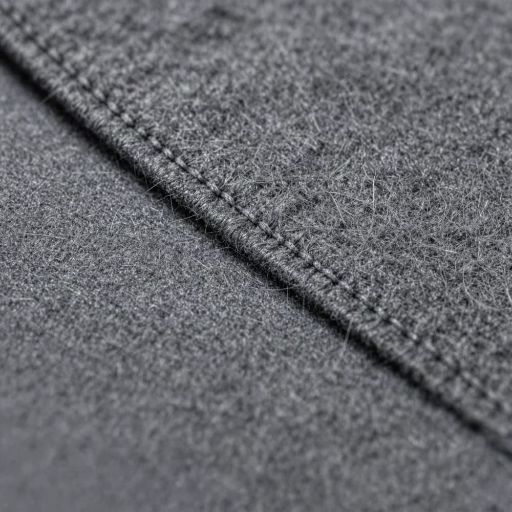 Close-up of hand pick-stitching along a wool lapel edge