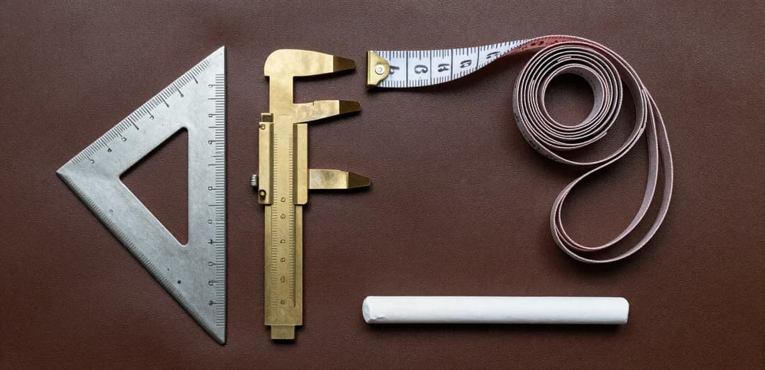 Tailoring tools arranged on a dark leather surface